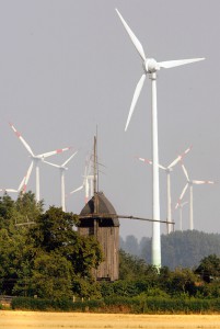 An old windmill stands in front of power-generating windmill turbines from a wind farm near the village of Ostingerslebe